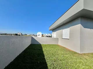 Fachada moderna de uma residência com jardim gramado sob um céu azul claro.