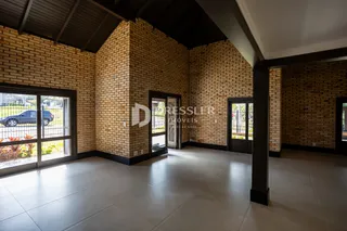 Interior de uma sala com paredes de tijolo aparente e piso de cerâmica.