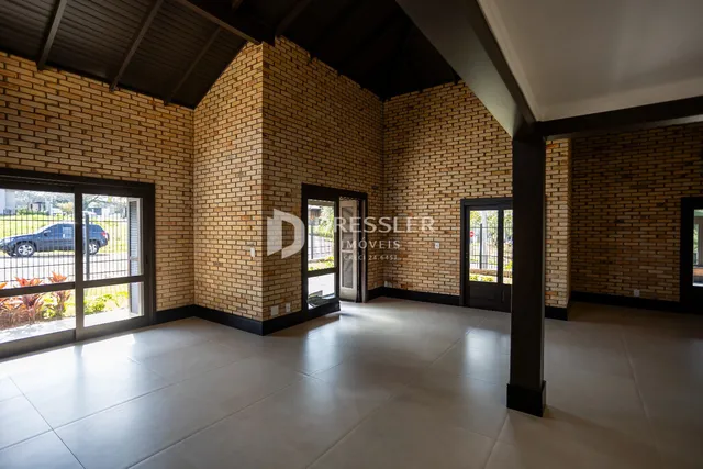 Interior de uma sala com paredes de tijolo aparente e piso de cerâmica.
