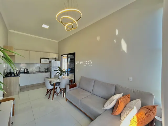 Sala de estar com cozinha integrada e piso de cerâmica clara.