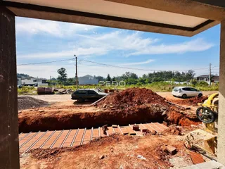 Vista de uma área de terra em construção com material de construção e um veículo no fundo.