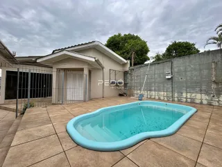 Vista externa de uma casa com piscina e muro de concreto.