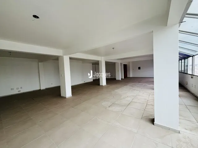 Imagem de um espaço interno amplo com colunas brancas e piso de cerâmica.