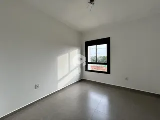 Ambiente interno de uma sala com paredes brancas e piso cinza.