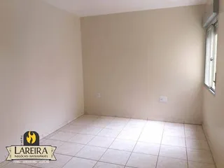 Imagem de uma sala vazia com paredes brancas e piso de cerâmica.