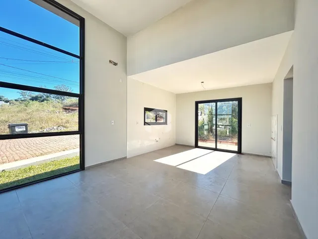 Sala de estar com grandes janelas de vidro e piso de concreto.