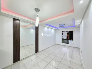 Vista interna de um corredor com piso de cerâmica clara e paredes brancas.