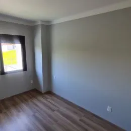 Interior de uma sala com piso de madeira clara.