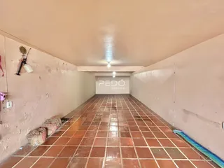 Corredor interno com piso de tijolos avermelhados em uma residência.