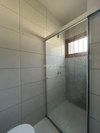 Foto de um banheiro com revestimento de azulejos claros e box de vidro.