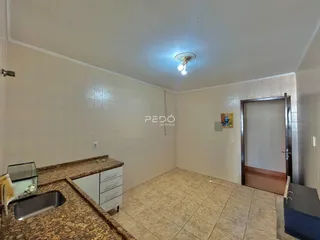 Vista interna de uma cozinha com piso de cerâmica e bancada de granito.