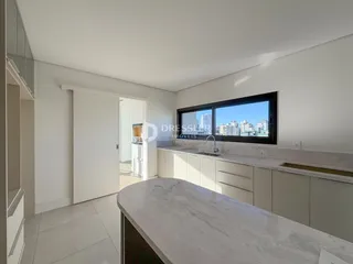 Vista da cozinha com bancada de mármore e janela para a cidade.
