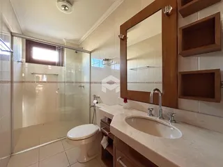 Foto de um banheiro com box de vidro e bancada de mármore.
