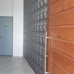 Parede com revestimento texturizado cinza e porta de madeira em um ambiente interno.