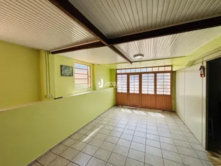 Uma área interna longa com paredes verdes e piso de cerâmica.