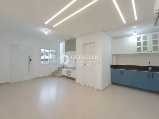 Sala de estar e cozinha de um apartamento moderno com piso claro.