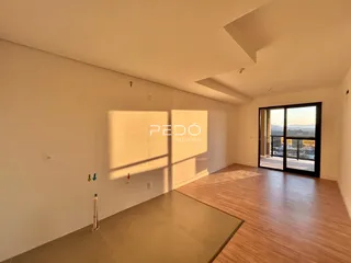 Sala de estar com piso de madeira e paredes brancas em um imóvel no Brasil.