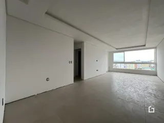 Vista interna de um cômodo amplo com paredes brancas e piso de concreto.