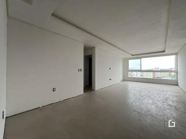 Vista interna de um cômodo amplo com paredes brancas e piso de concreto.