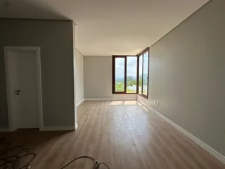 Sala de estar com piso de madeira e janela com vista para a paisagem.