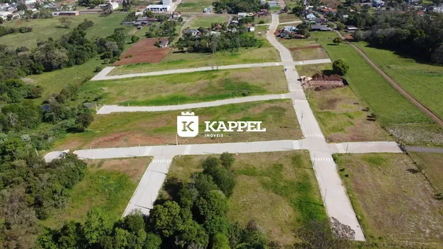 Vista aérea de um terreno aberto com campos gramados e estradas rurais.