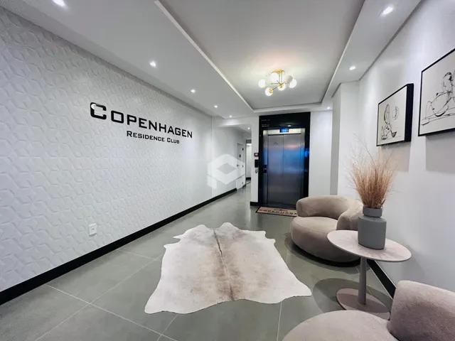 Hall de entrada moderno com paredes brancas e piso claro.