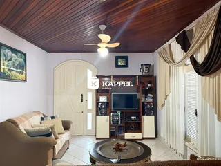 Sala de estar com sofá e painel de televisão em ambiente com teto de madeira.