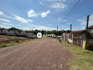 Uma estrada de terra leva a uma propriedade residencial sob um céu azul.