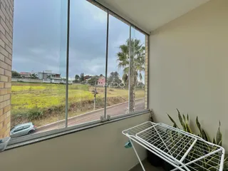 Vista da janela mostrando um campo aberto e vegetação no exterior.
