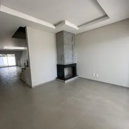 Ambiente interno de uma sala ampla com piso de concreto e estrutura de lareira.