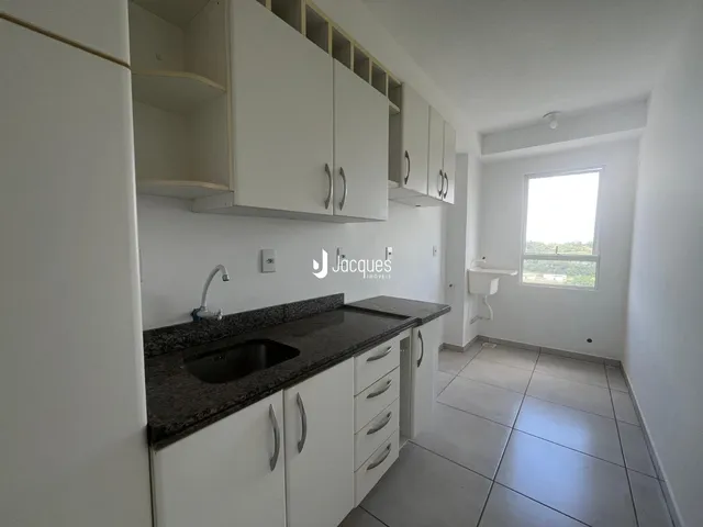 Vista da cozinha com armários brancos e bancada escura.
