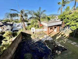 Vista externa da propriedade mostrando a área do jardim e uma estrutura coberta.