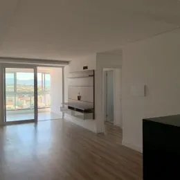 Sala de estar com piso de madeira e porta de vidro que dá para o exterior.