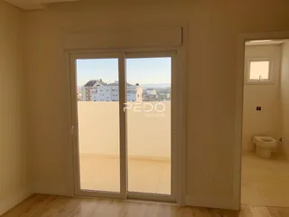 Vista de uma sala de estar com portas de vidro que dão para uma paisagem urbana.