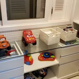 Detalhe de uma bancada com armários brancos e objetos decorativos em uma cozinha.