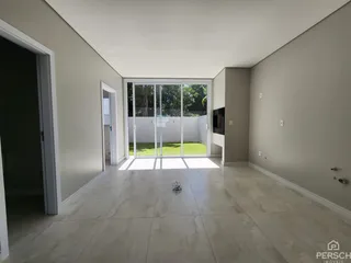 Sala de estar com piso de porcelanato e porta de vidro que dá acesso ao jardim.