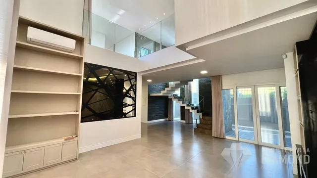 Sala de estar de uma residência com pé direito alto e grandes janelas.