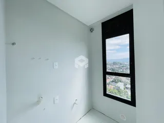 Vista interna de um cômodo com paredes brancas e uma grande janela.
