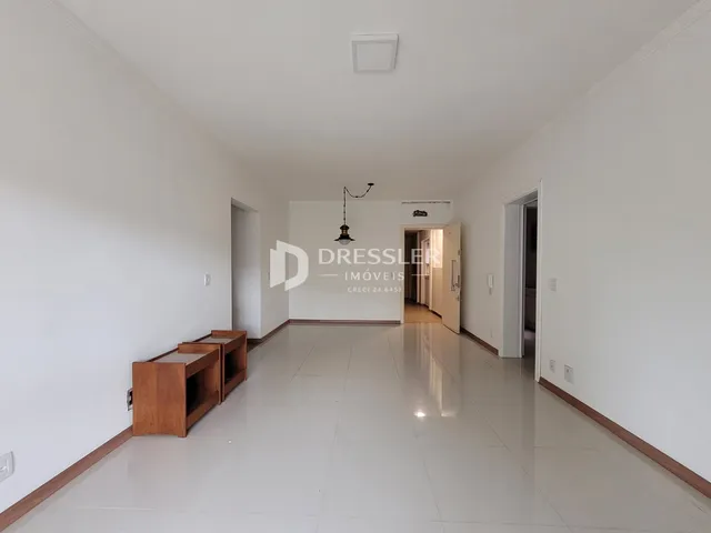 Interior de um corredor com piso claro e paredes brancas.