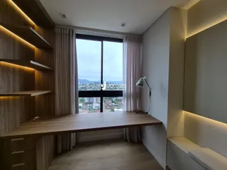 Cozinha moderna com bancada de madeira e iluminação embutida, com vista para a paisagem urbana.