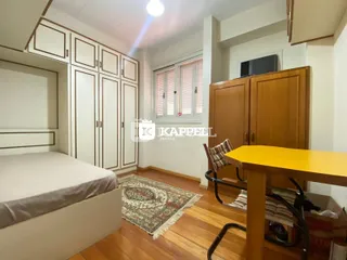 Quarto com cama e armários de madeira em um ambiente claro.
