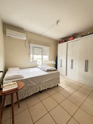Quarto com cama de casal e armário branco, com janela e ar-condicionado.