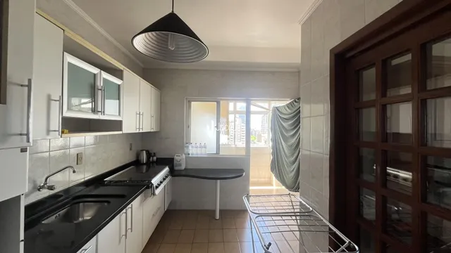 Cozinha com armários brancos e piso de cerâmica na residência.