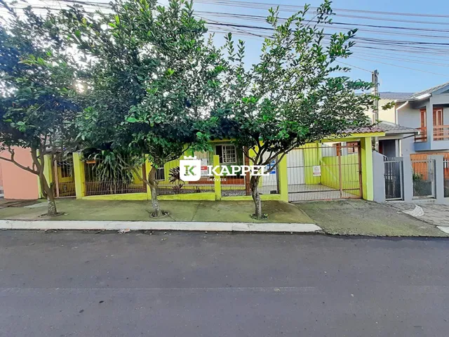 Foto da fachada de uma residência em Lajeado, Brasil, com vegetação e cerca na frente.