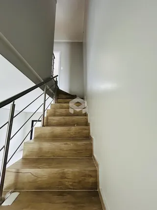 Escadaria de madeira com corrimão metálico em um ambiente interno.
