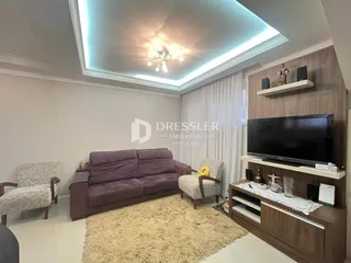 Sala de estar com sofá roxo e painel de TV.