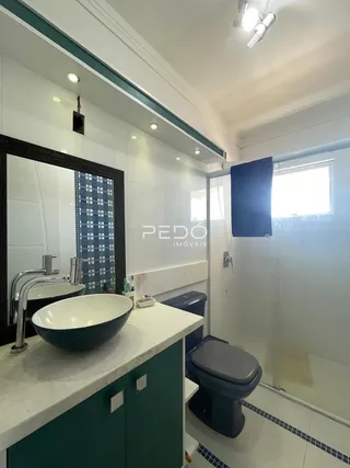 A foto mostra o interior de um banheiro moderno com pia e vaso sanitário.