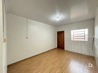 Foto de um cômodo interno com piso de madeira clara e paredes brancas.