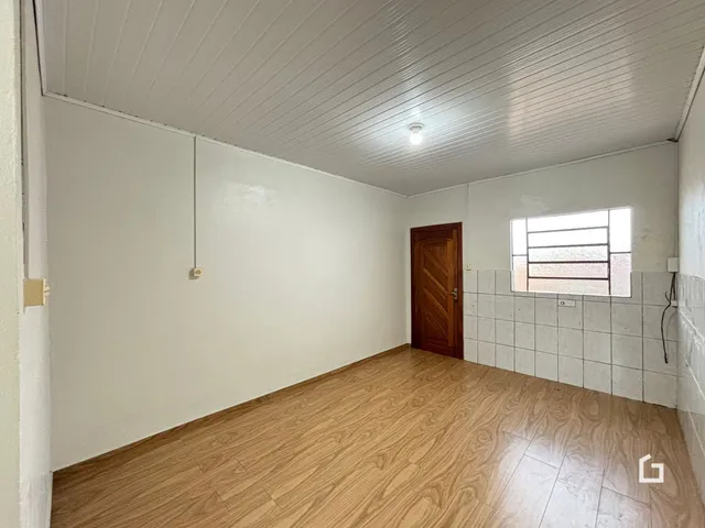Foto de um cômodo interno com piso de madeira clara e paredes brancas.