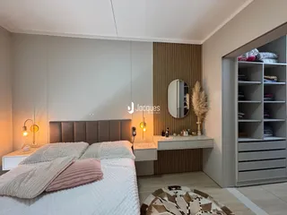 Quarto moderno com cabeceira estofada e armário embutido.